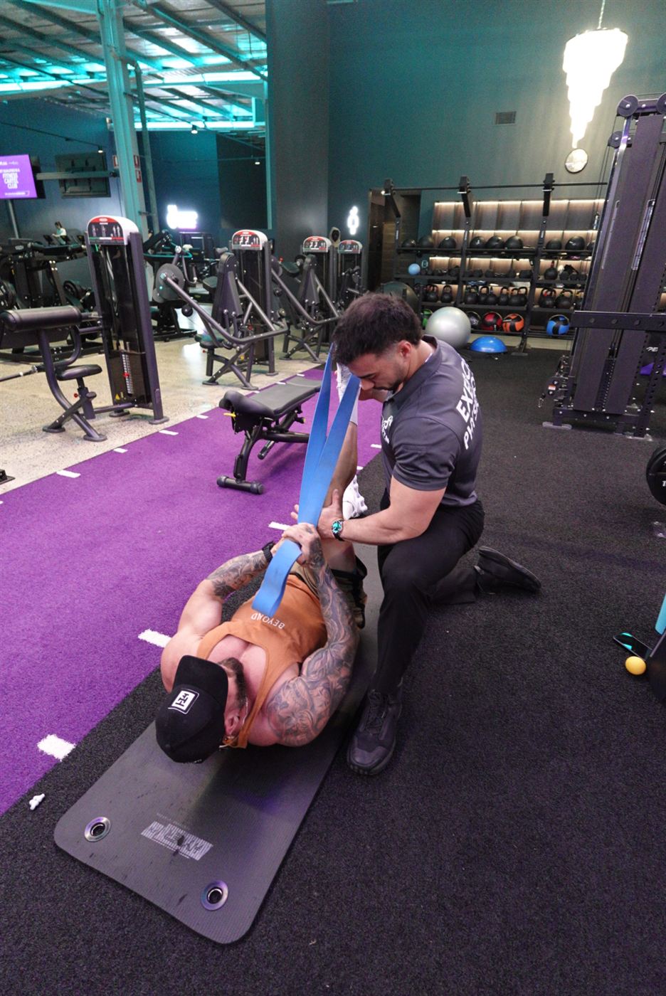A SYSTM exercise physiologist assisting a client with a resistance-band stretch